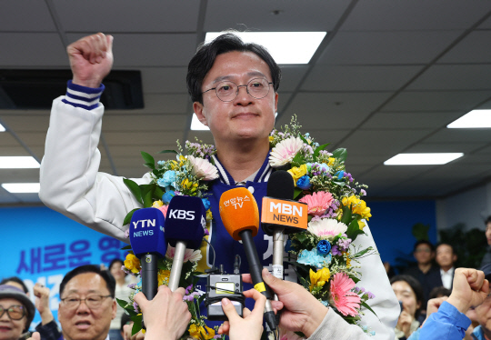 22대 총선 서울 영등포구갑에 출마한 더불어민주당 채현일 후보가 11일 영등포구에 마련된 본인의 선거사무소에서 당선이 확실시되자 밝은 표정으로 꽃목걸이를 걸고 방송 인터뷰 중 주먹을 쥐어보이고 있다.   [연합뉴스]
